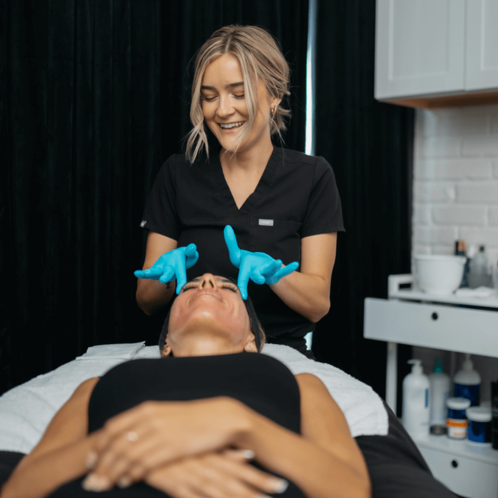 Cosmetologist holding woman's face in hands - Young Female Getting Skin Treatment | Refined Aesthetics in Olmos Park, Texas